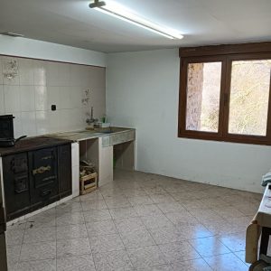 Cocina rústica con cocina de leña y fregadero de piedra en casa de pueblo en Laño, Condado de Treviño