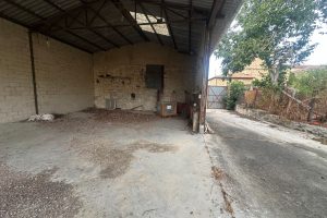 Zona interior de parcela urbana en Armiñón, Álava, con espacio cubierto, estructura metálica y patio pavimentado.