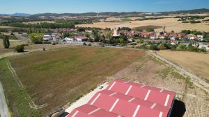 Vista aérea de terrenos junto al núcleo de La Puebla de Arganzón, Burgos, con una nave agrícola en primer plano.
