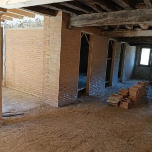 Txoko con vigas de madera y divisiones interiores de ladrillo en casa de pueblo en Laño, Treviño
